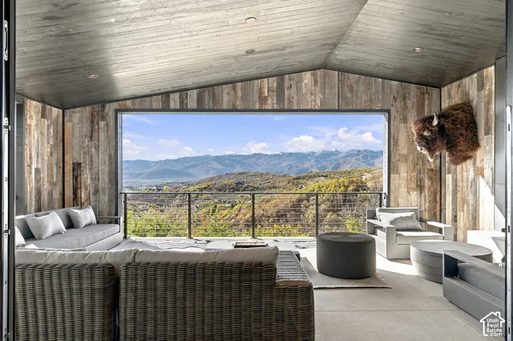 Covered outdoor office space featuring horizontal wood-plank walls and ceiling, concrete flooring, and metal cable railing with expansive views toward Park City