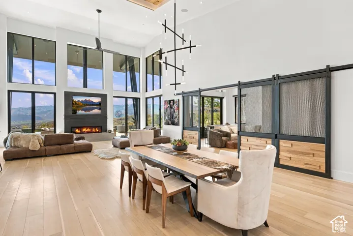 Double-height ceilings with floor-to-ceiling windows, linear fireplace with custom surround, wood-finish flooring, and pass through views toward Park City