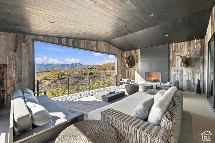 Covered outdoor office space featuring horizontal wood-plank walls and ceiling, concrete flooring, and metal cable railing with expansive views toward Park City