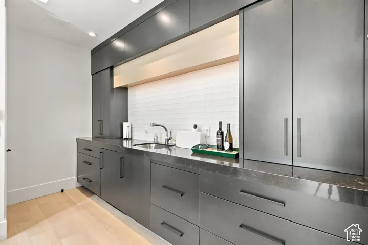 Custom built-in wetbar in guest quarters with integrated under-cabinet lighting, a white horizontal tile backsplash, quartz countertops