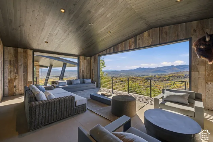 Covered outdoor office space featuring horizontal wood-plank walls and ceiling, concrete flooring, and metal cable railing with expansive views toward Park City
