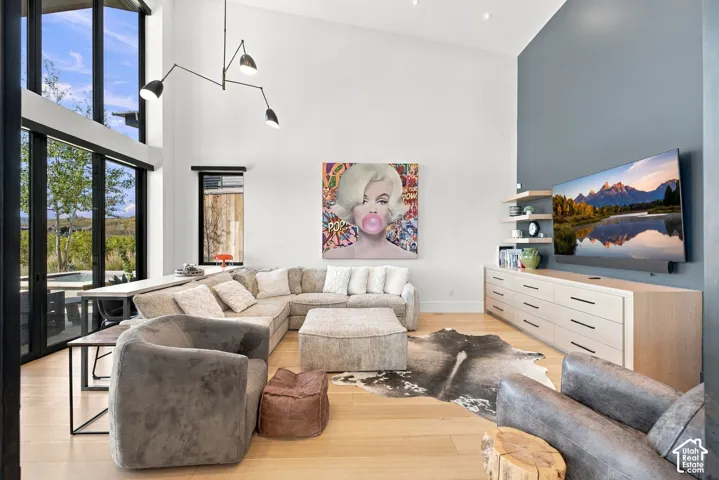 Den with vaulted ceilings, floor-to-ceiling windows feautring mountain views, wood-finish flooring, accent wall, and built-in cabinetry