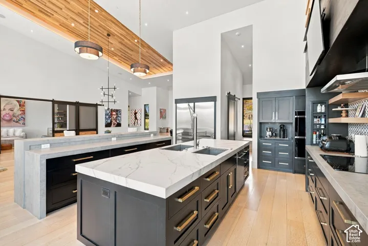 Kitchen featuring a wood-plank ceiling, double center islands with stone-surface countertops, custom cabinetry with metallic hardware, and wide-plank wood-finish flooring