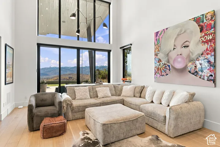 Den with vaulted ceilings, floor-to-ceiling windows feautring mountain views, wood-finish flooring, accent wall, and built-in cabinetry