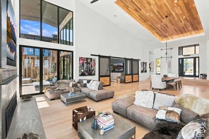 Great room featuring floor-to-ceiling windows, wood-finish flooring, vaulted ceilings with wood-plank inlay, modern metal-frame sliding doors, and a linear fireplace