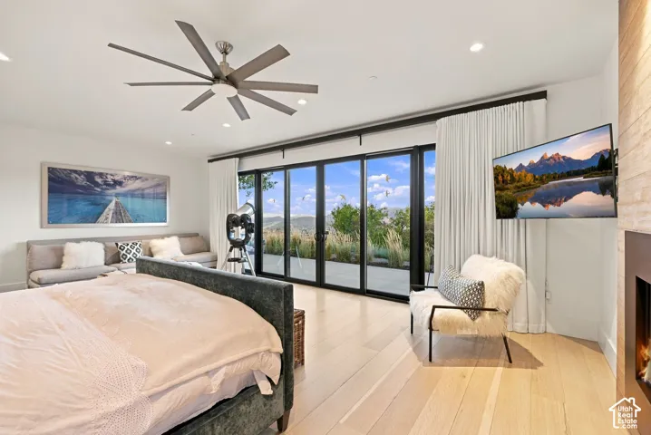 Floor-to-ceiling multi-panel sliding glass doors, wood-finish flooring, recessed lighting, ceiling fan, and built-in fireplace