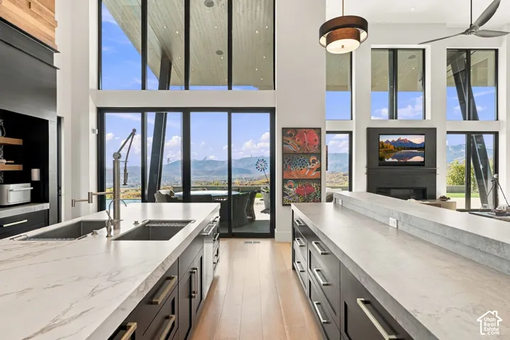Kitchen featuring dual islands with expansive stone countertops, custom dark cabinetry, wood-finish flooring, floor-to-ceiling windows, and mountain scenery