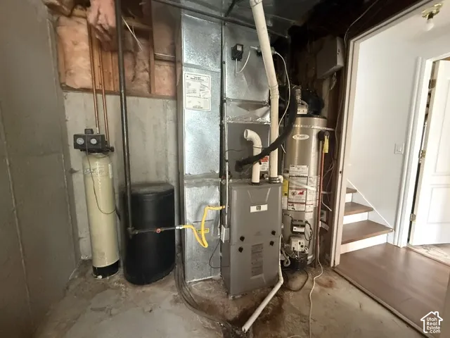 Mechanical room featuring a high-efficiency forced-air furnace, vertical water heater, water softener system, and exposed ductwork