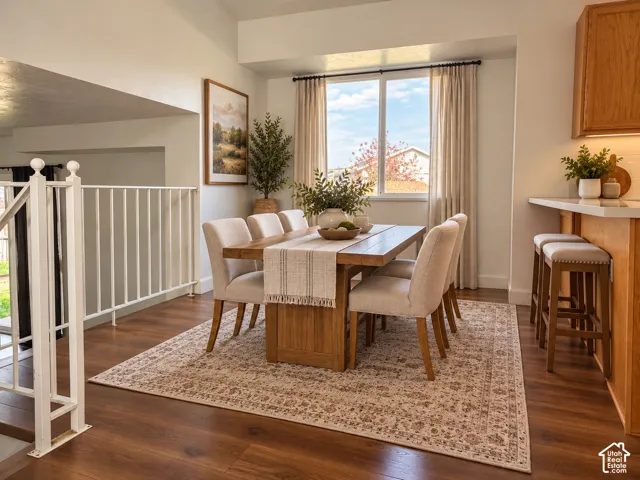 Dining space featuring wood-finish flooring, a large window with natural light, and a white metal staircase railing