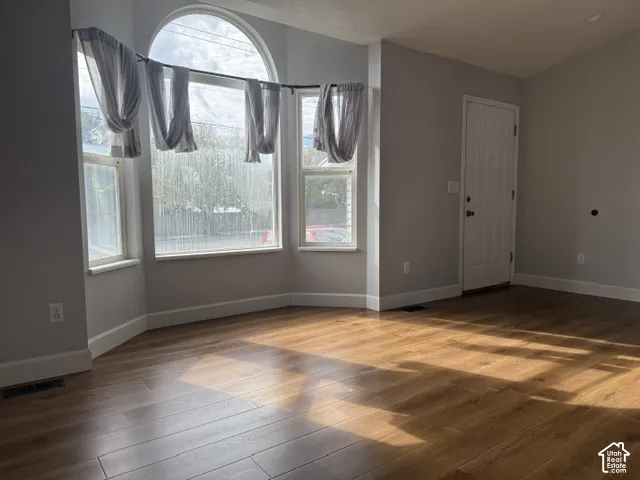 Wood-finish flooring, expansive bay window with arched top, and crisp neutral wall paint