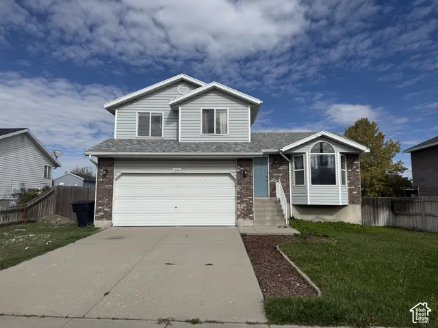Two-story exterior featuring horizontal siding, brick veneer accents, a multi-pane bay window, an attached two-car garage, and a concrete driveway