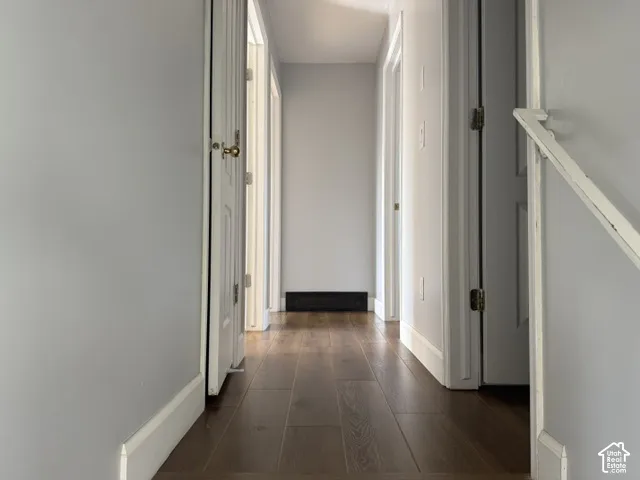 Hallway featuring wood-finish flooring, white paneled doors, and painted neutral walls