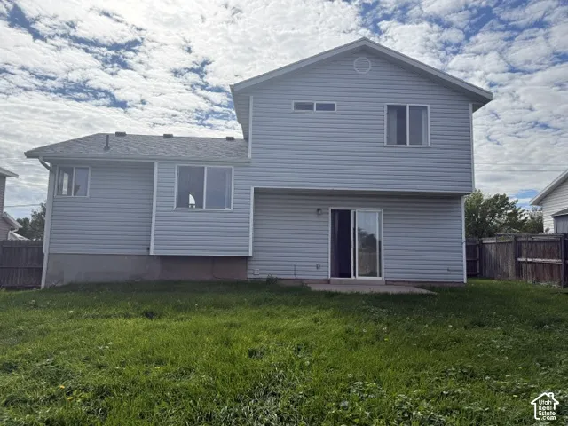 Exterior featuring light-colored horizontal siding, asphalt shingle roofing, sliding glass door access, concrete patio, and fenced perimeter