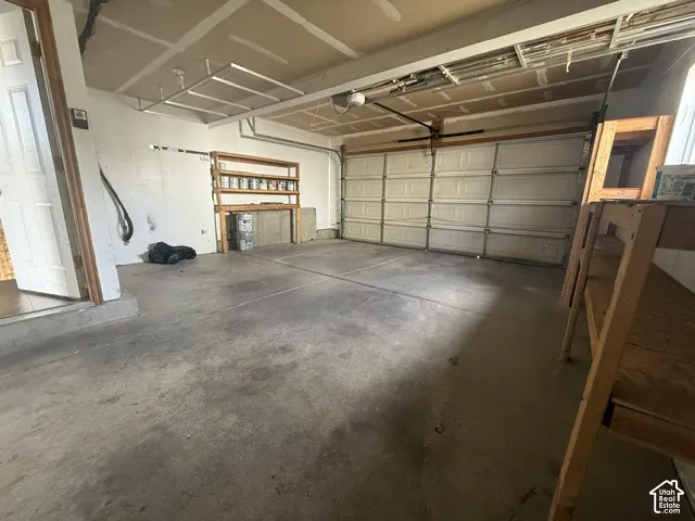 Multi-car garage featuring a concrete floor, sectional overhead door, and wall-mounted shelving units