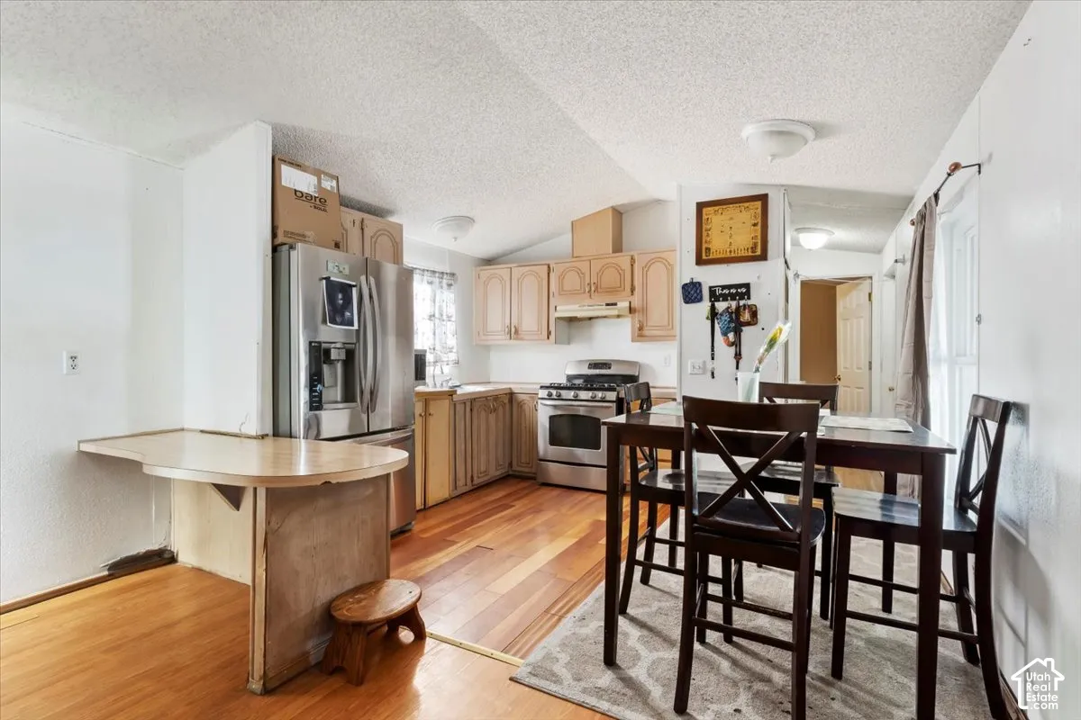 Kitchen featuring wood-finish flooring, stainless steel appliances, and wood cabinetry