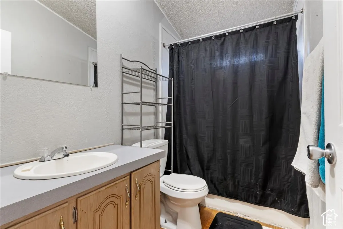 Bathroom featuring a vanity with wood-finish cabinetry, an integrated sink, a single-handle faucet, and a wall-mounted mirror