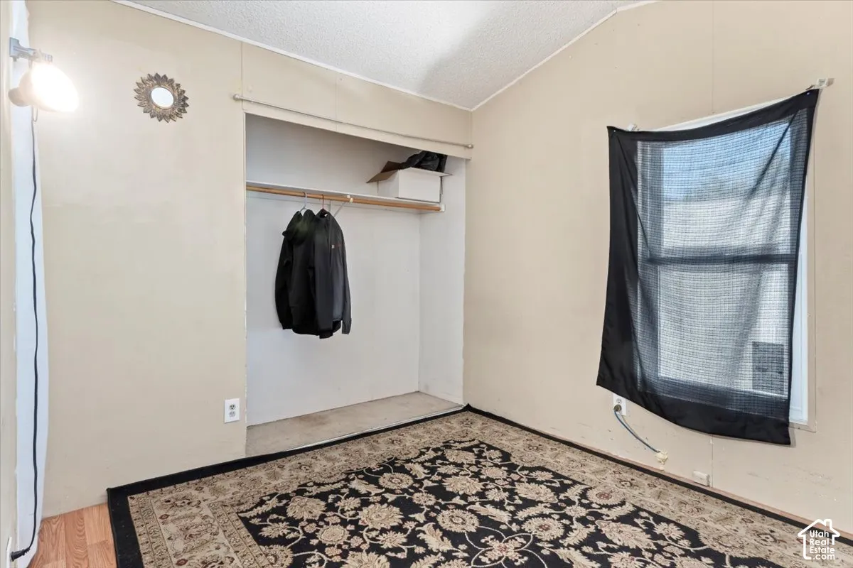 Room featuring wood-finish flooring, a built-in closet with overhead shelving, and a single-hung window