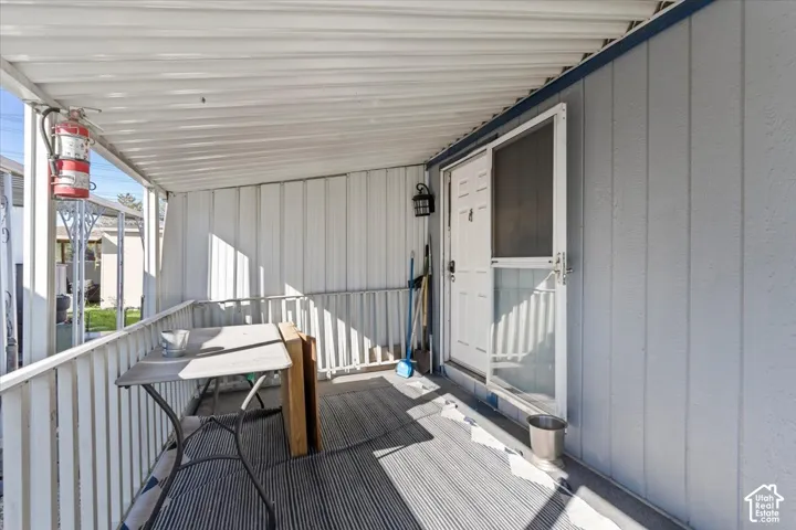 Covered porch featuring vertical metal siding, white aluminum railings, and a screen-door entry