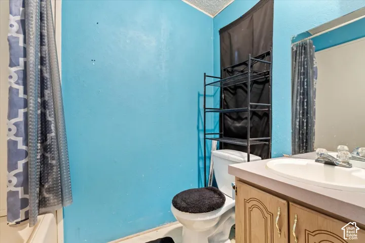 Bathroom featuring a vanity with a laminate countertop, inset oval sink, and wood-finish cabinetry