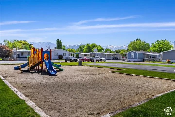 Common outdoor space featuring playground equipment, a paved basketball court, turf areas, and a mountain backdrop