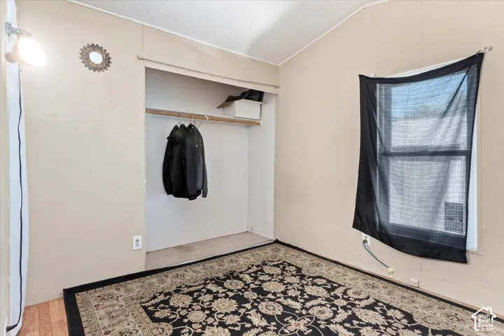Room featuring wood-finish flooring, a built-in closet with overhead shelving, and a single-hung window
