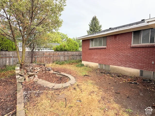 Red brick exterior with stone retaining wall, landscape masonry, mature trees, and wood fencing