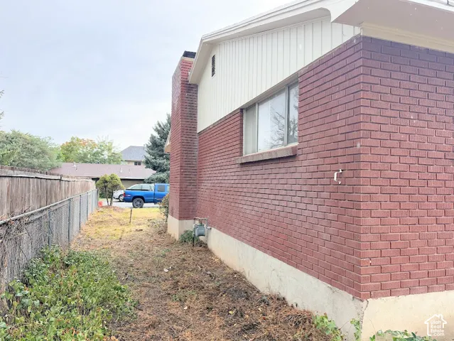 Exterior side profile featuring red brick masonry, vertical siding, and an external brick chimney