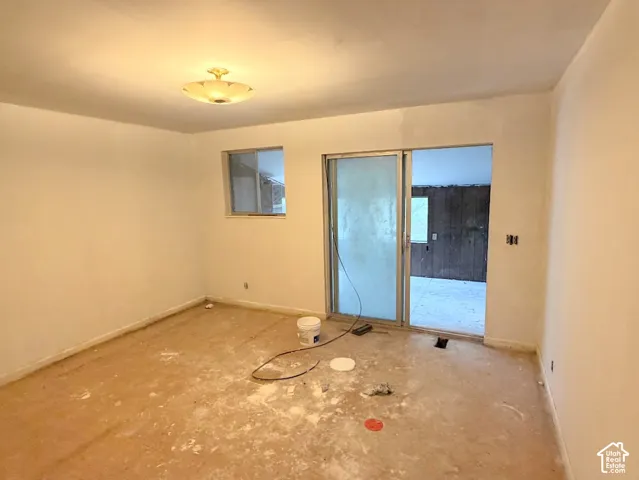 Room featuring smooth wall finishes, a metal-framed sliding glass door, a rectangular window, and a semi-flush mount ceiling fixture