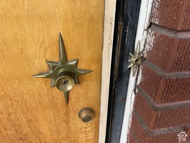 Flat-grain wood door featuring metallic starburst-motif door hardware and a matching star-shaped doorbell plate, set within a red brick exterior frame