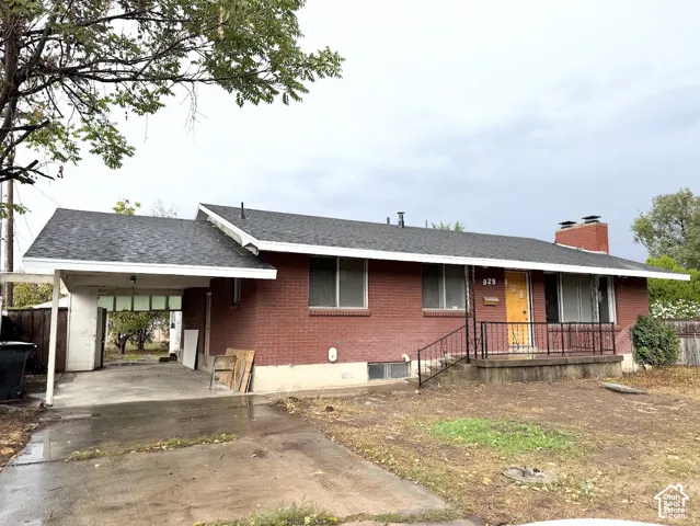 Single-story brick exterior featuring a covered carport, an elevated front porch with black iron railings, and a brick chimney