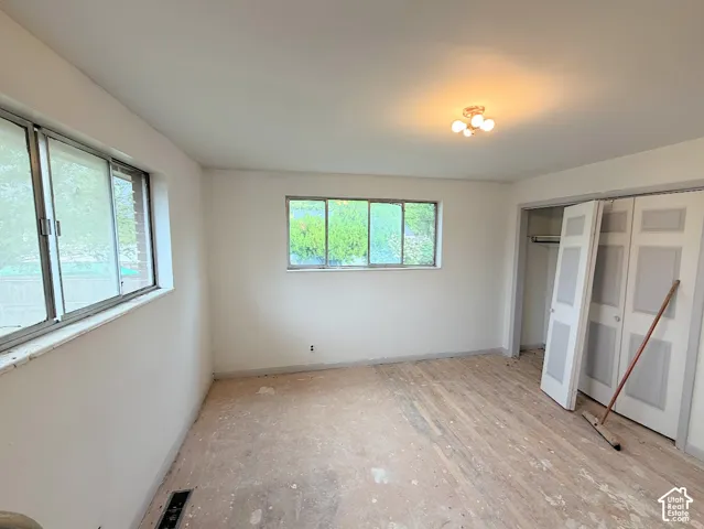 Neutral-toned interior space featuring sliding-sash windows, hard surface flooring, and a multi-panel closet door