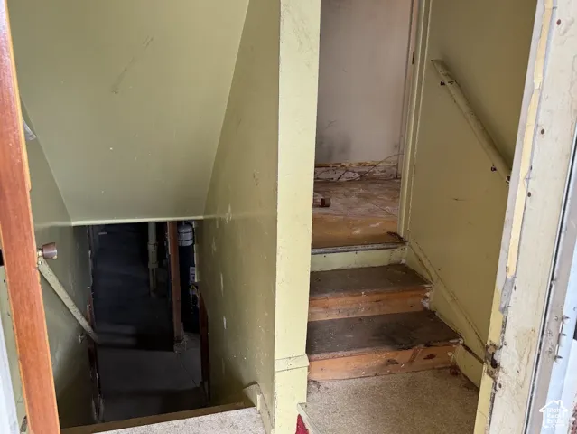 Staircase with wooden treads, painted wall finish, and mounted handrails