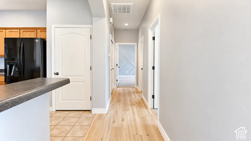 Hallway featuring wood-finish flooring, neutral wall paint, and multiple interior paneled doors