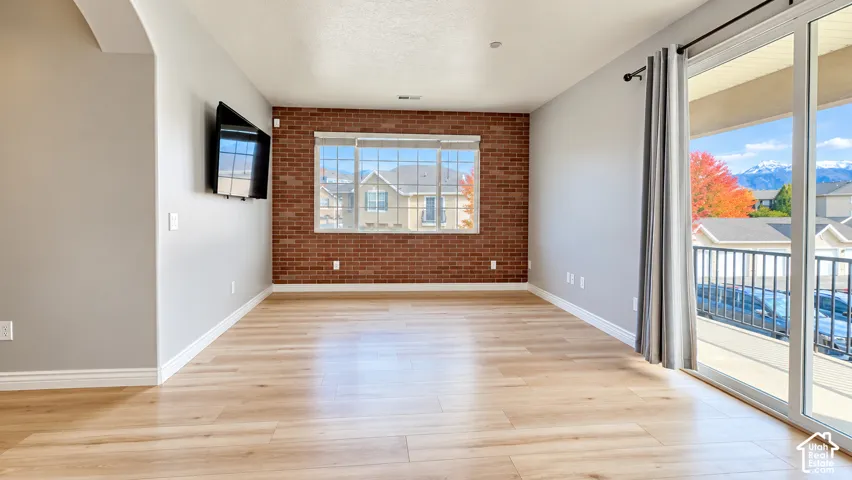 Exposed brick accent wall, wood-finish flooring, and sliding glass doors opening to a balcony with mountain scenery