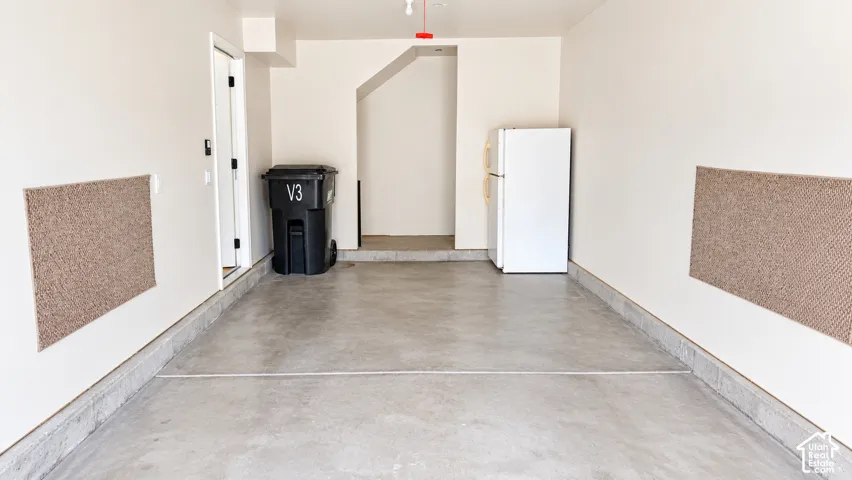 Finished garage featuring smooth concrete flooring, neutral-toned walls, and wall-mounted protective carpeting panels