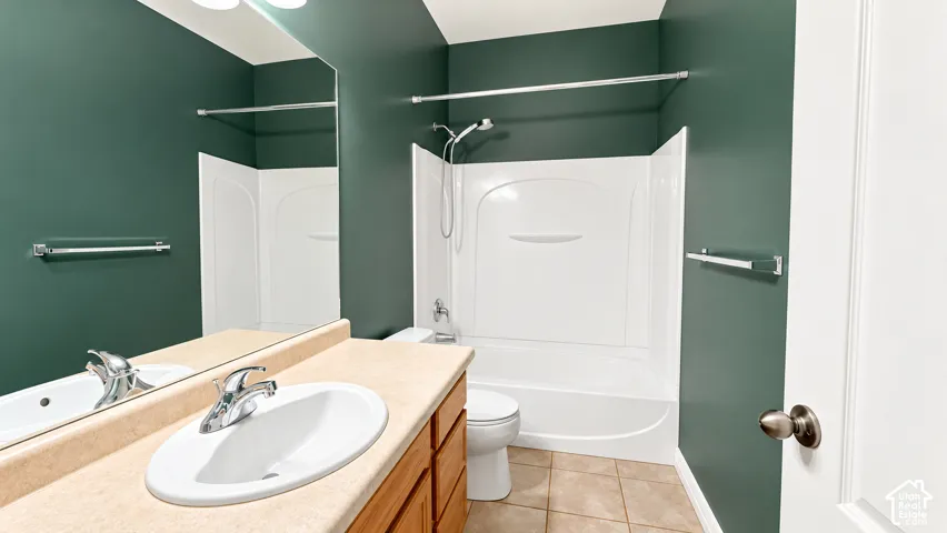 Bathroom featuring a vanity with a composite countertop and integrated basin, a tub-shower combination with a molded surround, large-format mirror, and tile flooring