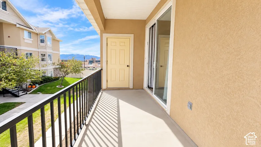 Covered balcony featuring concrete flooring, black metal railing, and a sliding glass door
