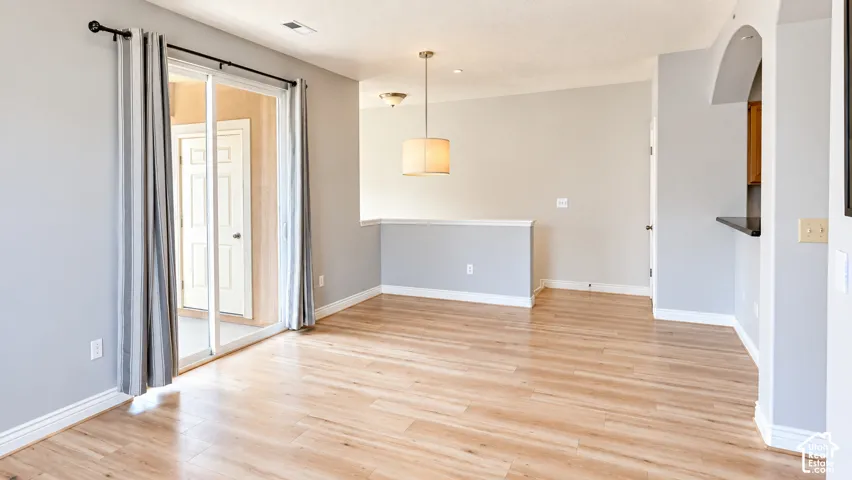 Wood-finish flooring, sliding glass door, drum pendant light fixture, and arched wall opening