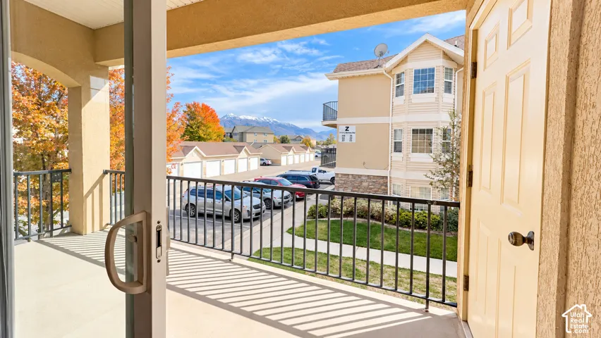 Covered balcony featuring concrete flooring, black metal railing, and mountain backdrop
