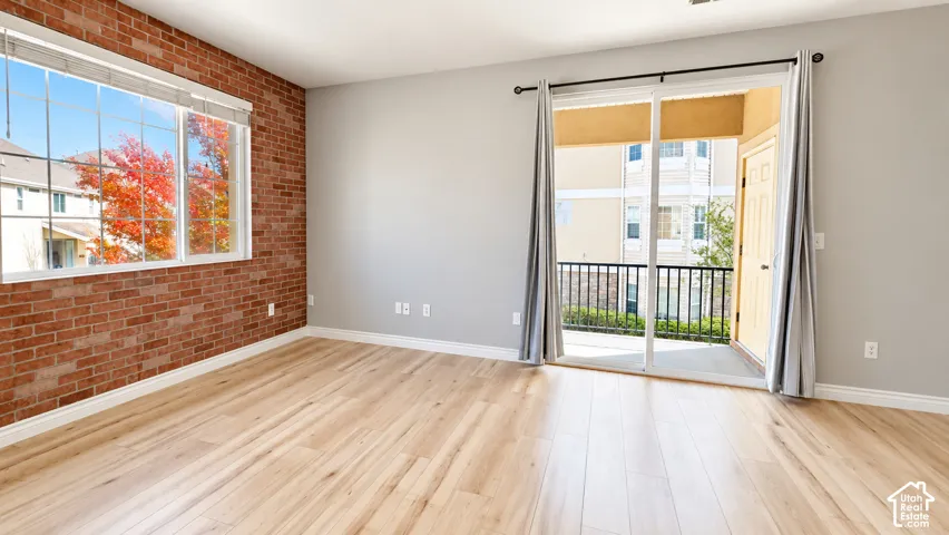 Exposed brick accent wall, wood-finish flooring, and glass sliding doors opening to a private balcony with metal railing