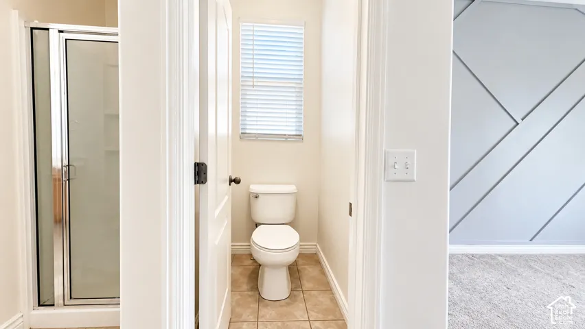 Enclosed shower with glass door, tile flooring, and geometric wall molding