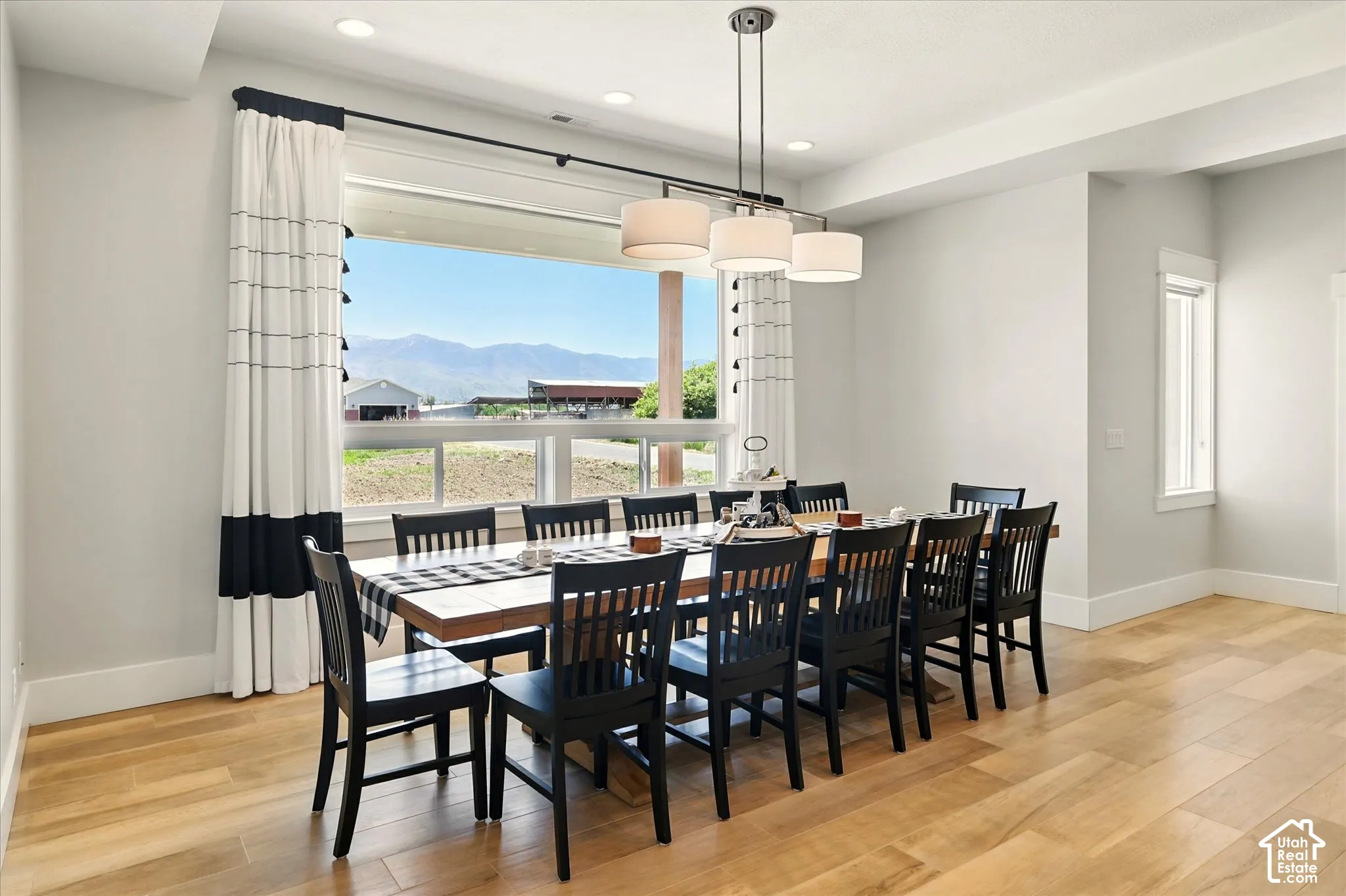 Dining area featuring wood-finish tile flooring, a three-light drum shade pendant fixture, and a large picture window showcasing mountain scenery