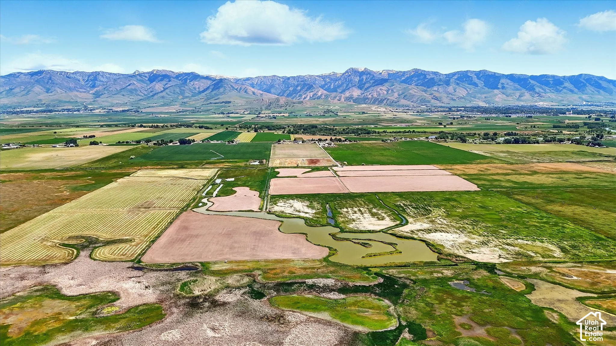 Expansive acreage featuring natural water channels, open terrain, and mountain backdrop