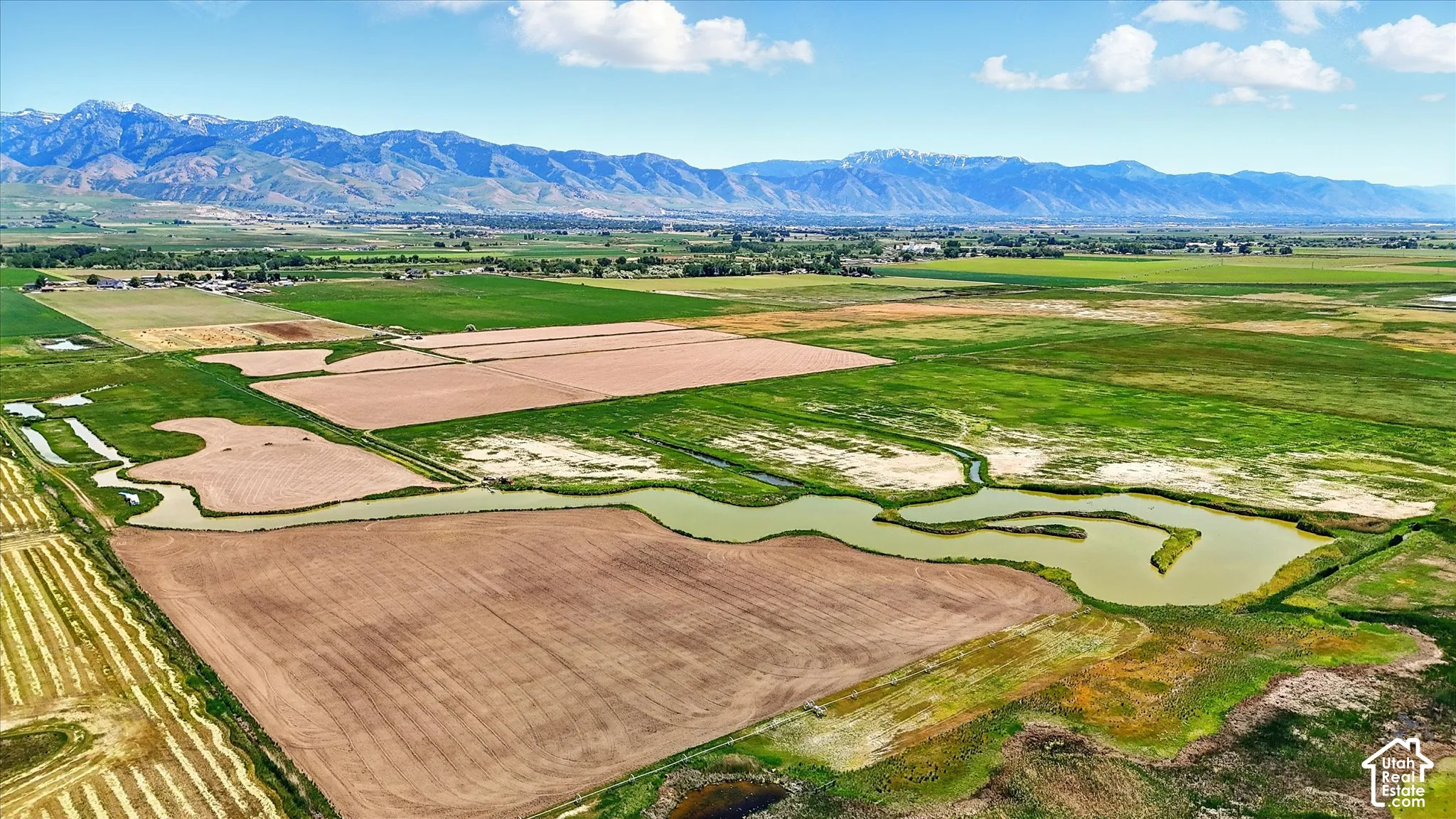 Expansive acreage featuring winding natural waterways, varied open terrain, and a prominent mountain backdrop