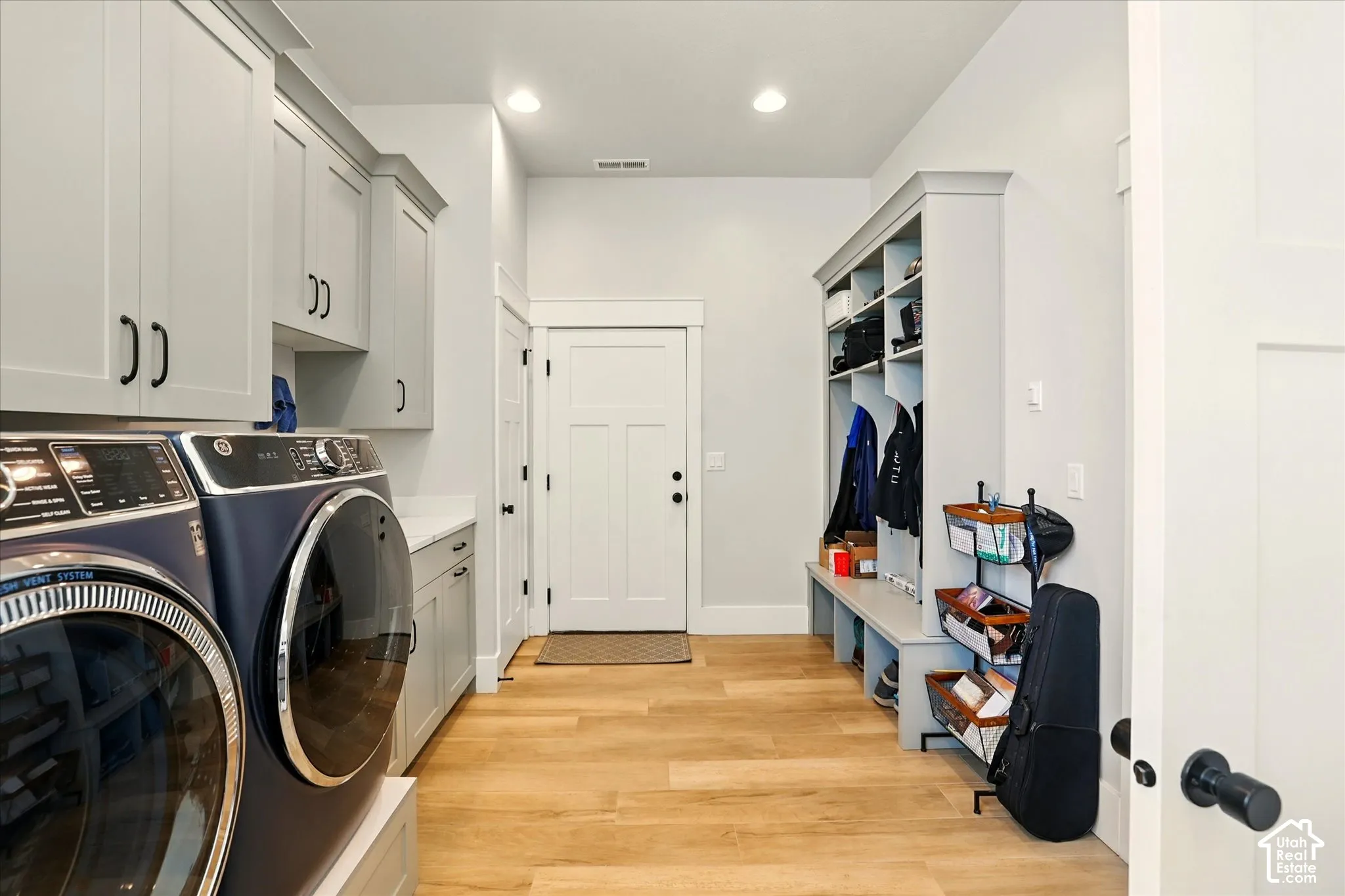 Laundry room featuring light grey cabinetry, solid surface countertops, recessed lighting, built-in mudroom lockers, and wood-finish flooring