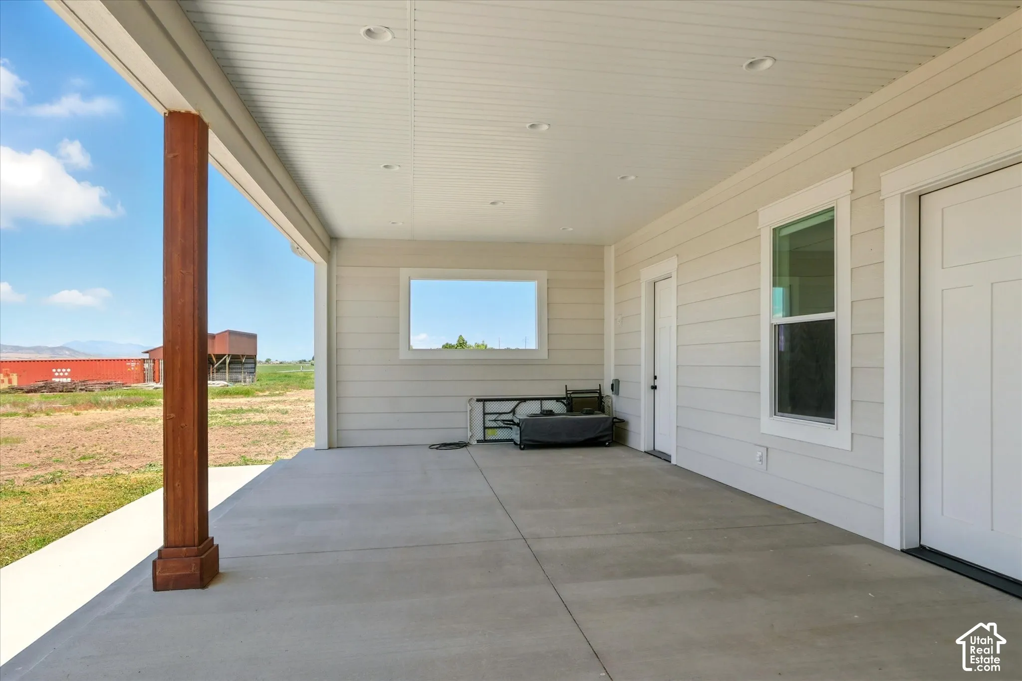 Covered patio featuring concrete flooring, a recessed-lighting ceiling, horizontal siding, a stained wood post, and a paneled entry door