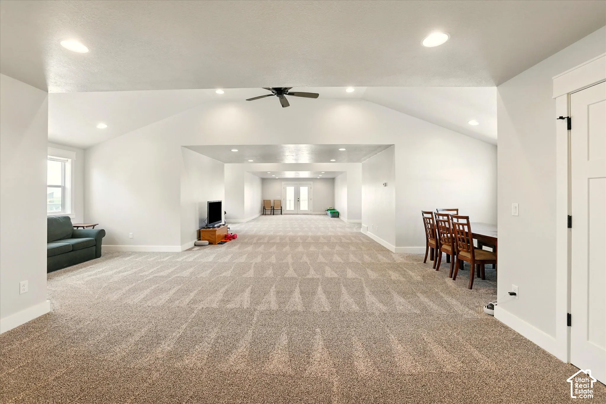 Open-concept bonus room featuring vaulted ceilings, recessed lighting, carpeted flooring, a ceiling fan, and double glass-panel doors leading onto upper deck