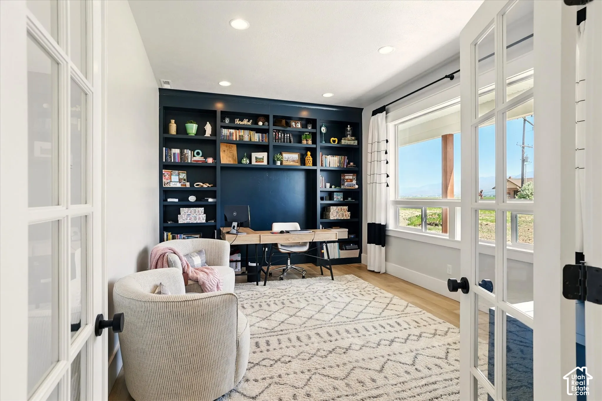 Built-in dark-toned cabinetry with open shelving, wood-finish flooring, recessed lighting, and French doors