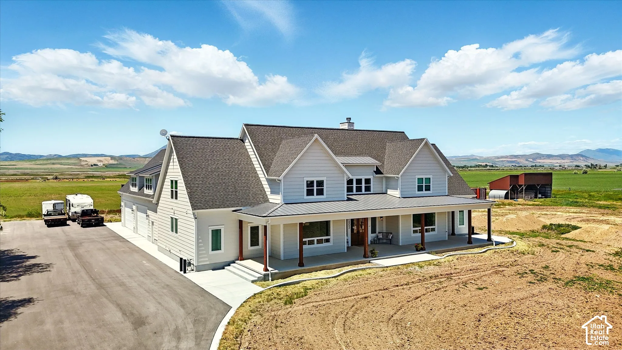 Two-story residence featuring horizontal siding, a covered front porch with timber-style pillars, a multi-gabled asphalt shingle roof, and a large paved driveway