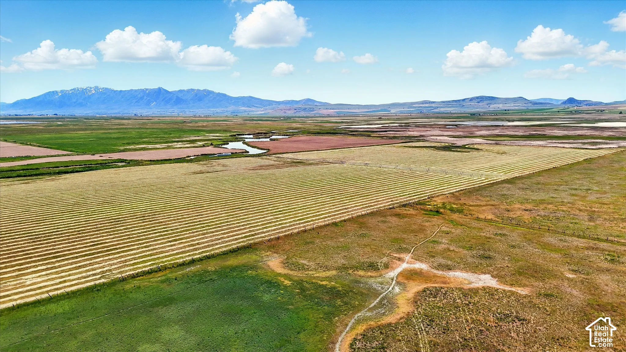 Expansive acreage featuring open fields, a natural waterway, and a prominent mountain range backdrop